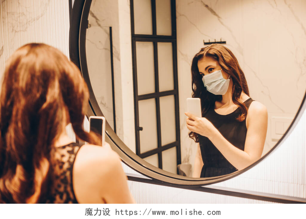 拿手机对镜子拍照的女人穿着黑色衣服和医疗面罩的女性在浴室拍照的选择性焦点